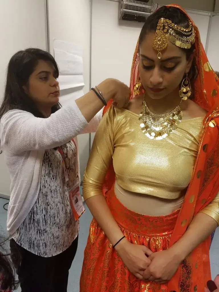 Bridal stylist adjusting traditional wedding outfit and jewelry
